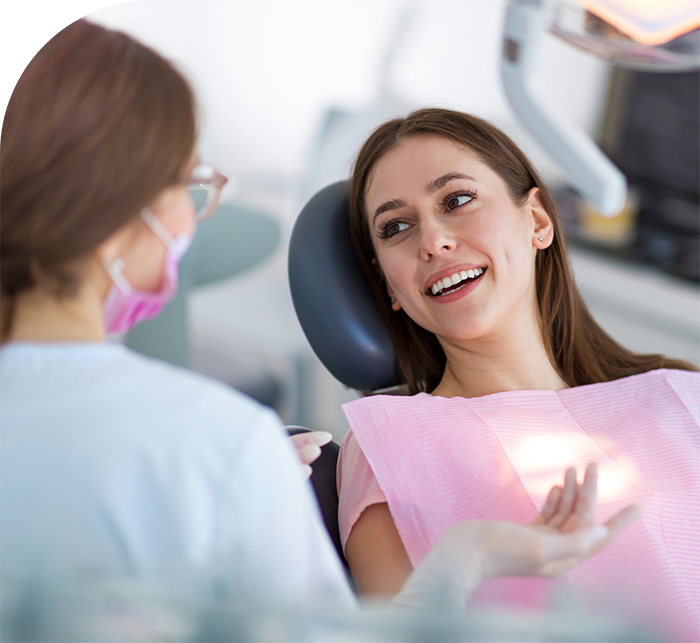 Woman in dental chair talking to her dentist in Hanover