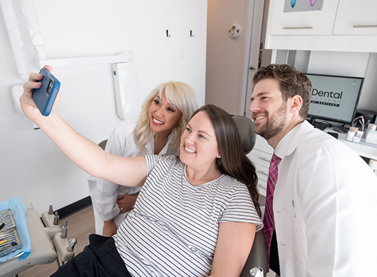 Dental patient taking a selfie with dentist and assistant