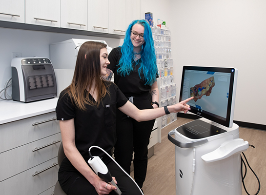 Dental team member pointing to monitor showing digital impressions of teeth