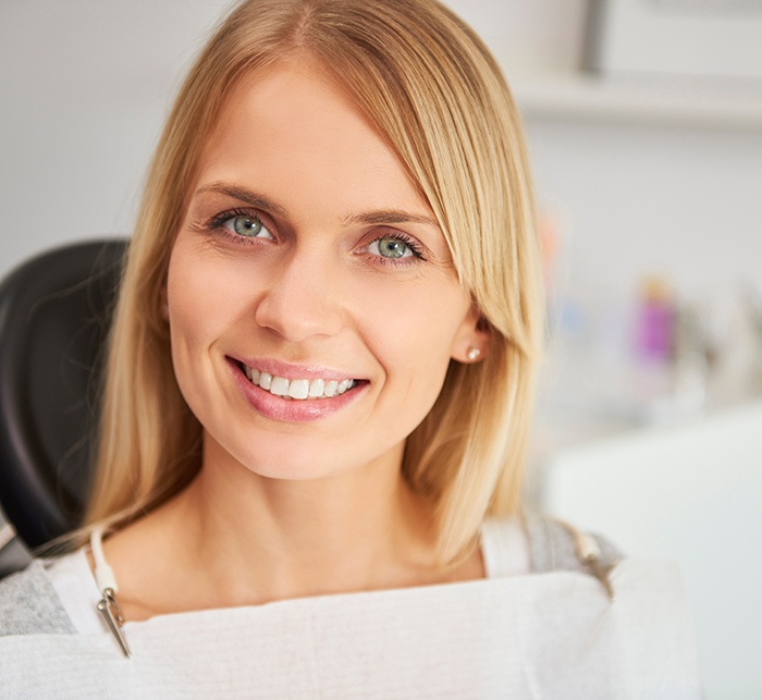Blonde woman sitting in dental chair smiling