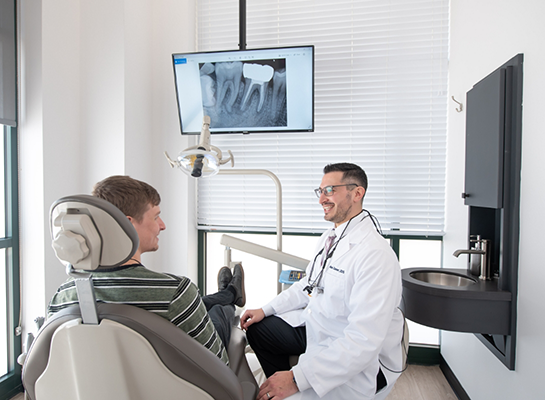 Dentist talking to young man in dental chair