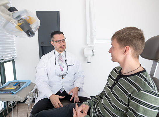 Young man in dental chair talking to his dentist