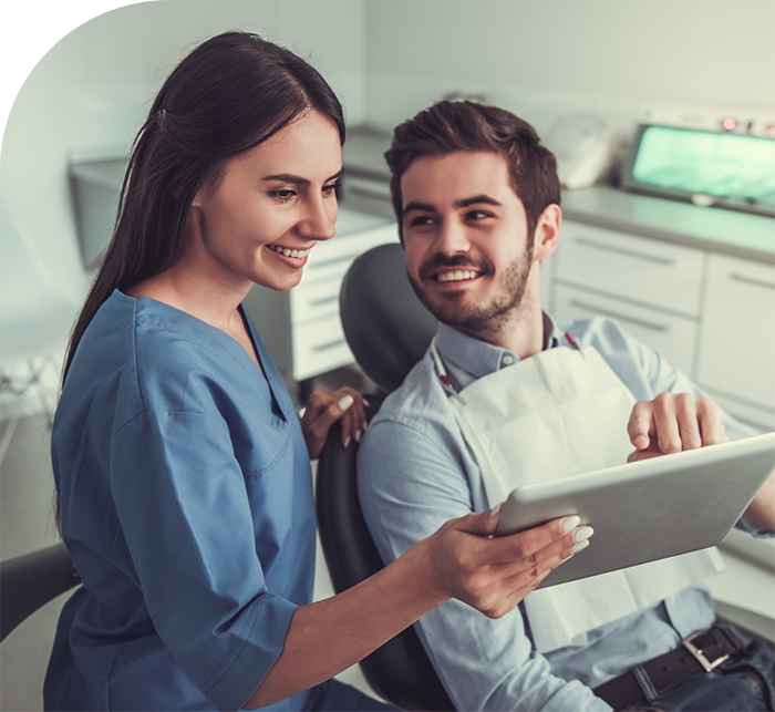 Dentist showing a patient a tablet after replacing missing teeth in Hanover