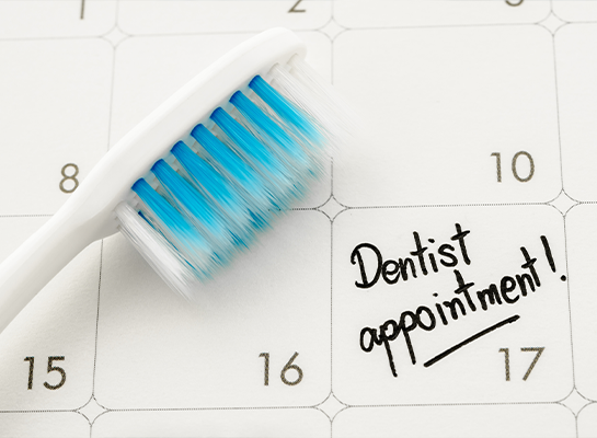 Toothbrush next to calendar showing date of dental appointment