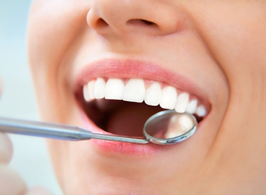 Close up of dental mirror next to smiling mouth