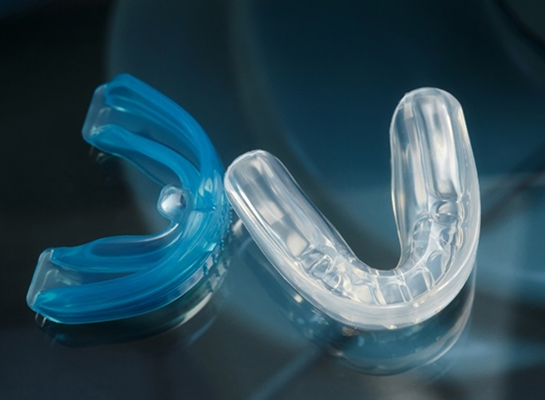 Clear mouthguard next to blue case