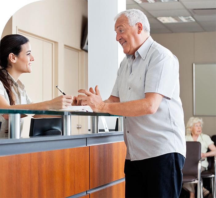 Senior man talking to receptionist at dental office in Hanover