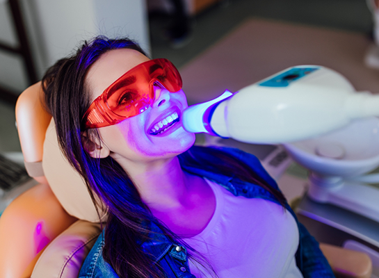 Woman in dental chair getting professional teeth whitening