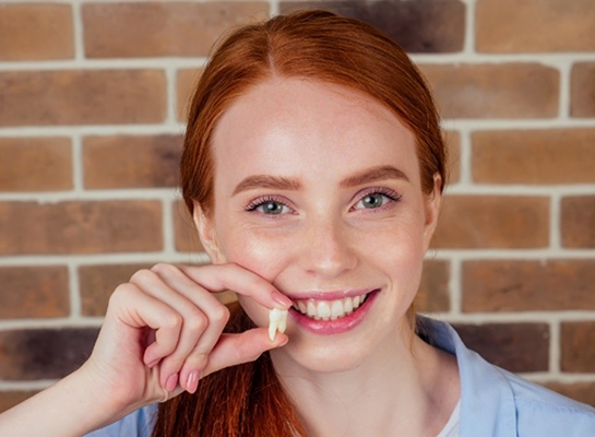 Smiling woman holding a tooth